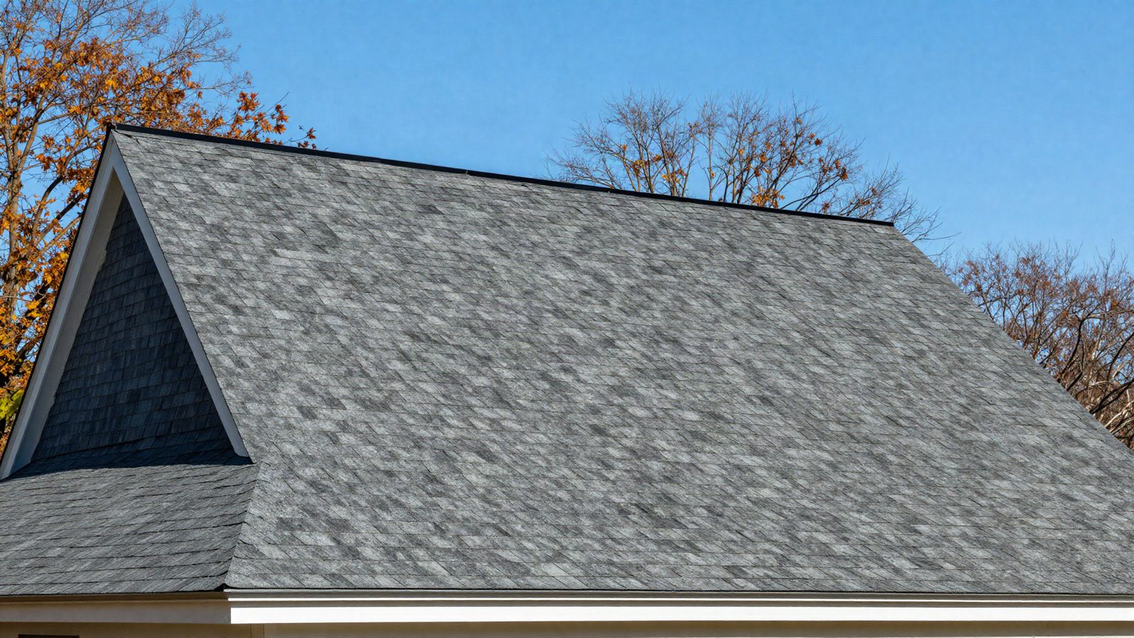A newly installed dark architectural shingle roof on a New England colonial house