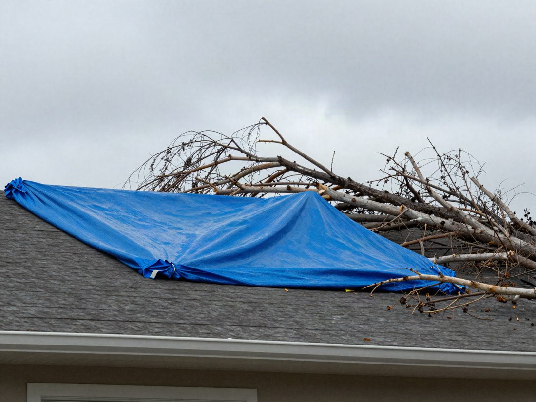 An emergency tarp secured over a storm damaged roof